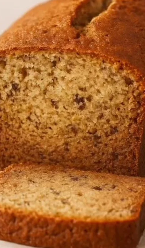 Classic Banana Bread Slice of homemade Classic Banana Bread with ripe bananas on a wooden table